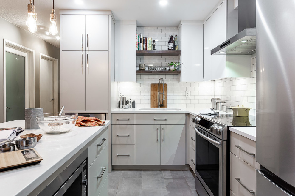 Idéer för små funkis vitt l-kök, med en undermonterad diskho, släta luckor, grå skåp, bänkskiva i kvarts, vitt stänkskydd, stänkskydd i tunnelbanekakel, rostfria vitvaror, cementgolv, en köksö och grått golv