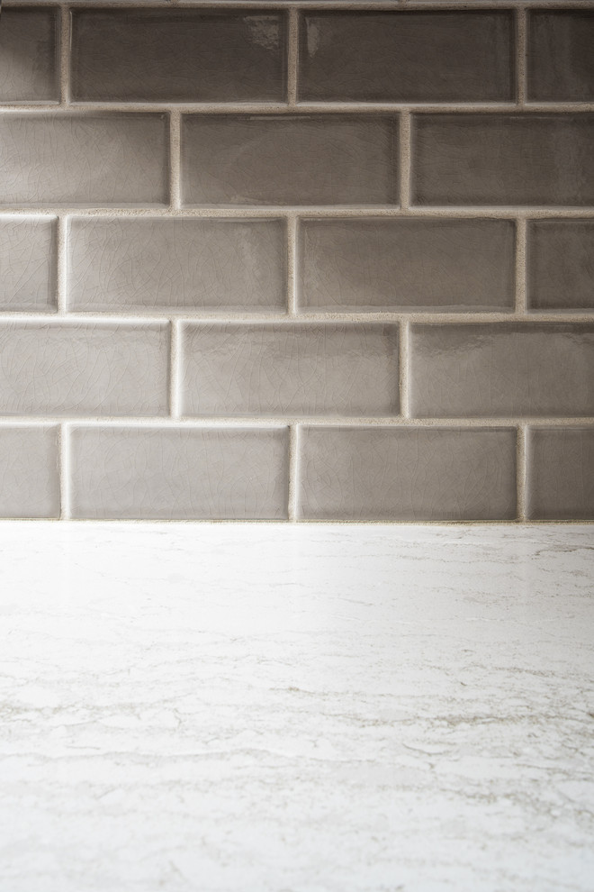 Bild på ett avskilt, litet vintage vit vitt l-kök, med en undermonterad diskho, skåp i shakerstil, vita skåp, bänkskiva i kvartsit, grått stänkskydd, stänkskydd i keramik, rostfria vitvaror, mellanmörkt trägolv och brunt golv