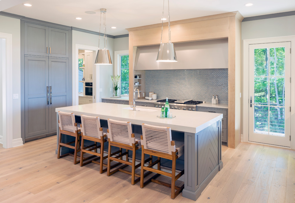 Inspiration for an expansive classic u-shaped open plan kitchen in Grand Rapids with a submerged sink, shaker cabinets, grey cabinets, engineered stone countertops, metallic splashback, integrated appliances, light hardwood flooring, an island, beige floors and white worktops.