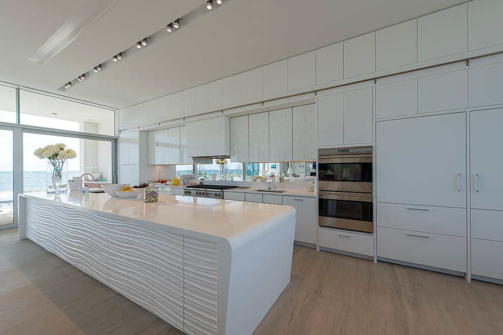 Cette image montre une cuisine américaine parallèle design avec un placard à porte plane, des portes de placard blanches et un électroménager en acier inoxydable.