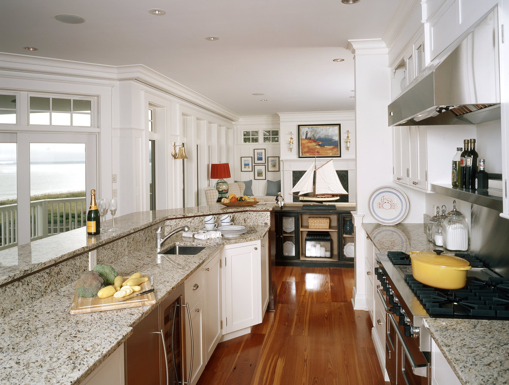 Aménagement d'une cuisine parallèle bord de mer avec un placard à porte shaker, des portes de placard blanches et un électroménager en acier inoxydable.