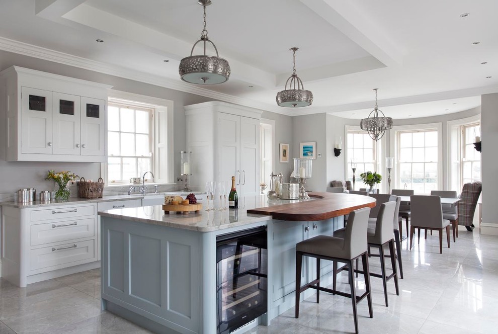 This is an example of an expansive classic l-shaped open plan kitchen in Other with a belfast sink, shaker cabinets, blue cabinets, marble worktops, grey splashback, stone slab splashback, black appliances, ceramic flooring and an island.