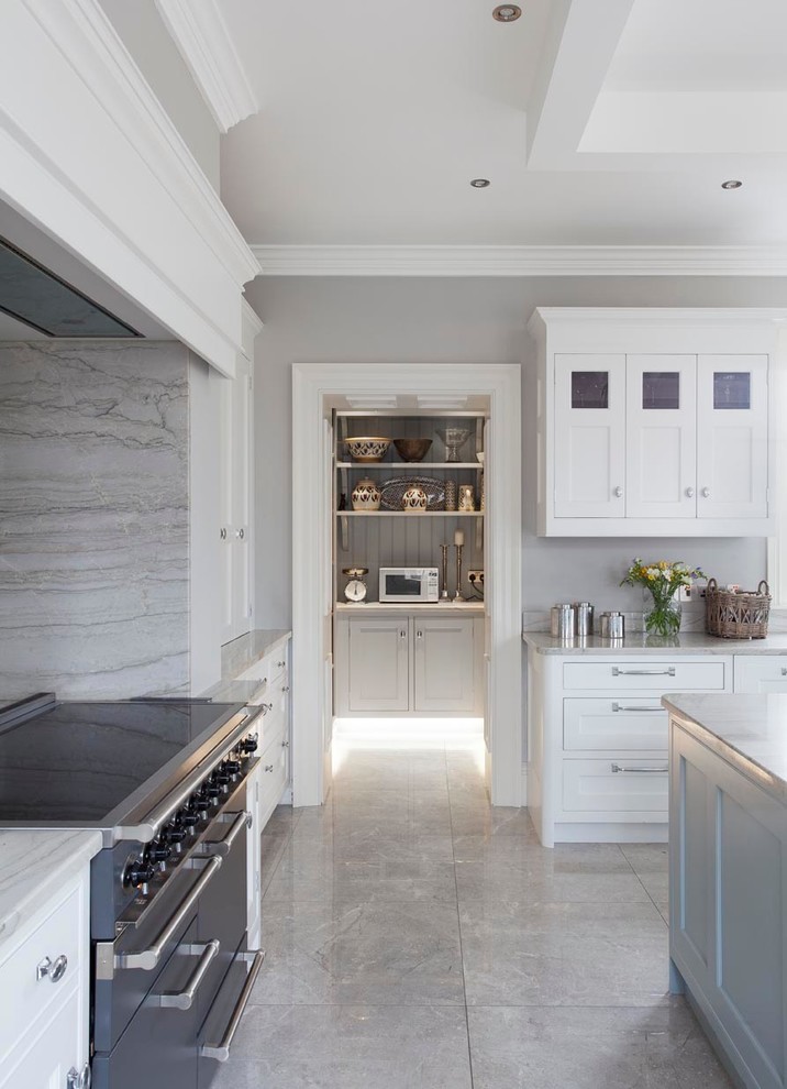 This is an example of an expansive traditional l-shaped open plan kitchen in Other with a belfast sink, shaker cabinets, blue cabinets, marble worktops, grey splashback, stone slab splashback, black appliances, ceramic flooring and an island.