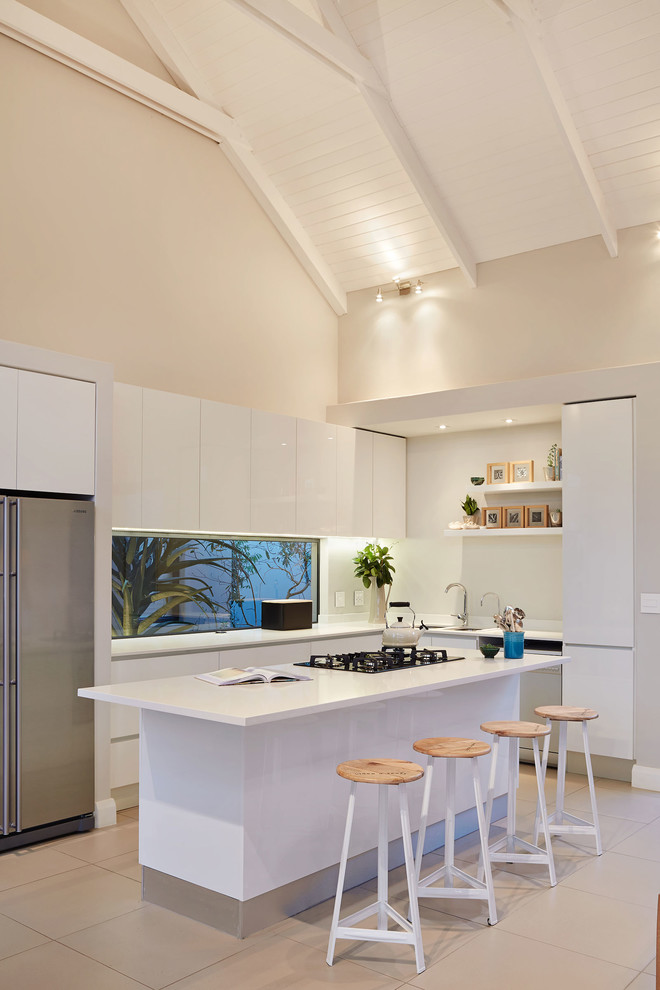 Inspiration for a contemporary l-shaped kitchen in Other with flat-panel cabinets, white cabinets, stainless steel appliances, a breakfast bar and beige floors.