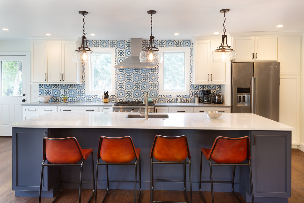 Bild på ett mellanstort vintage vit vitt kök, med bänkskiva i kvartsit, blått stänkskydd, stänkskydd i cementkakel, rostfria vitvaror, mörkt trägolv, en köksö, brunt golv, en undermonterad diskho, skåp i shakerstil och vita skåp