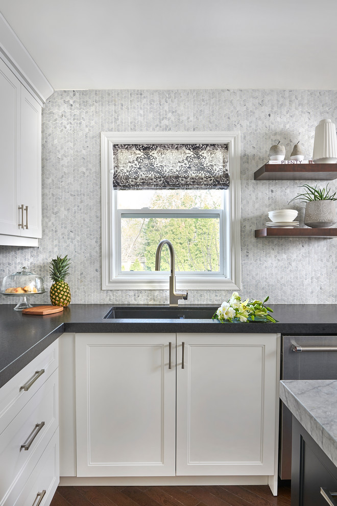 Foto på ett funkis kök, med skåp i shakerstil, vita skåp, marmorbänkskiva, vitt stänkskydd, stänkskydd i marmor, rostfria vitvaror, mellanmörkt trägolv och en köksö