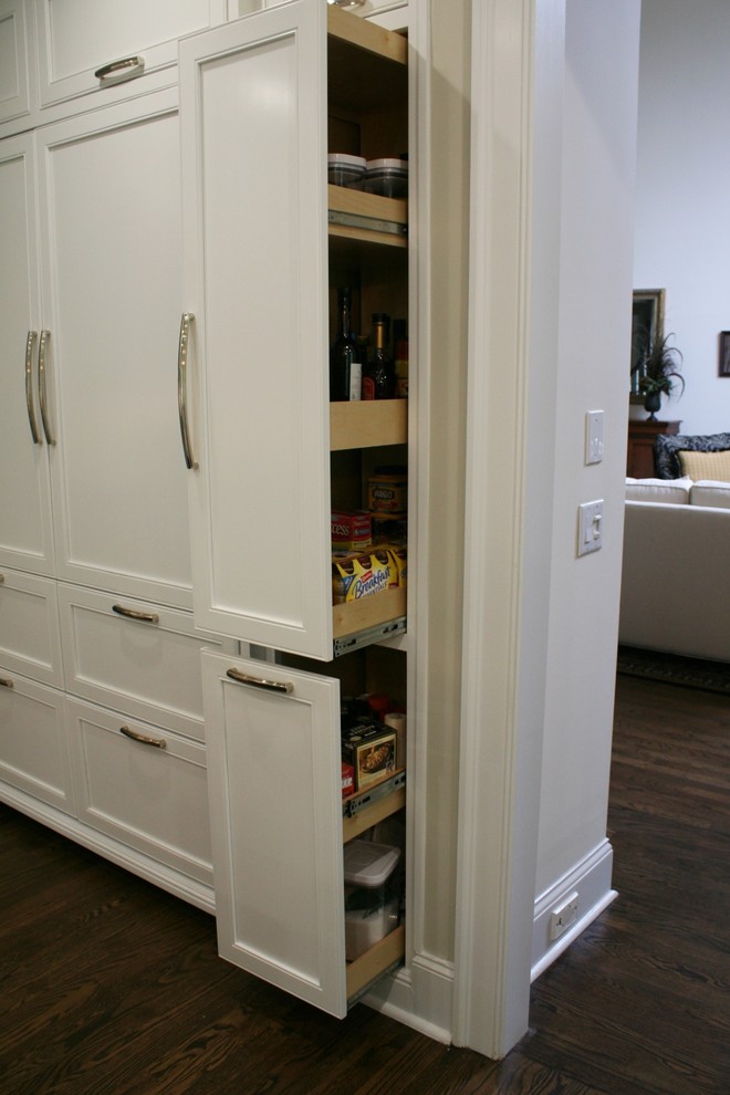 Ejemplo de cocina clásica renovada abierta con armarios tipo vitrina, electrodomésticos de acero inoxidable, suelo de madera en tonos medios y una isla