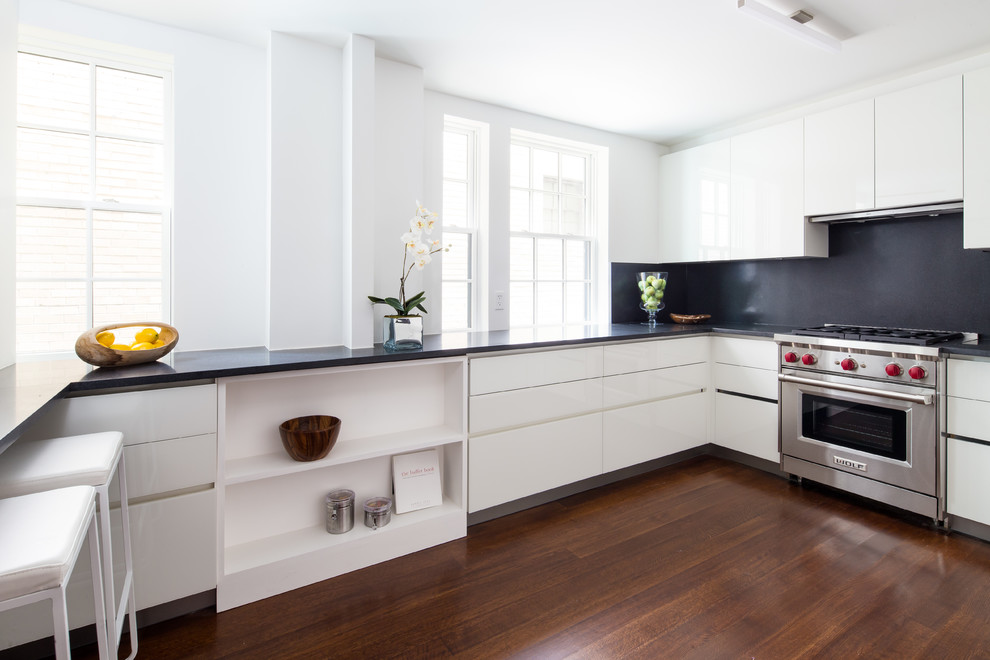 Moderne Küche in U-Form mit flächenbündigen Schrankfronten, weißen Schränken und Küchenrückwand in Schwarz in New York