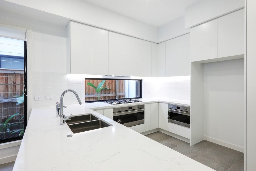 Moderne Küche mit Quarzwerkstein-Arbeitsplatte, Küchenrückwand in Weiß, Küchengeräten aus Edelstahl und weißer Arbeitsplatte in Gold Coast - Tweed