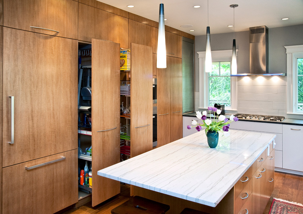 Mittelgroße Moderne Küche mit flächenbündigen Schrankfronten, hellbraunen Holzschränken, Marmor-Arbeitsplatte, Küchenrückwand in Weiß, Rückwand aus Porzellanfliesen, Küchengeräten aus Edelstahl und braunem Holzboden in Boston