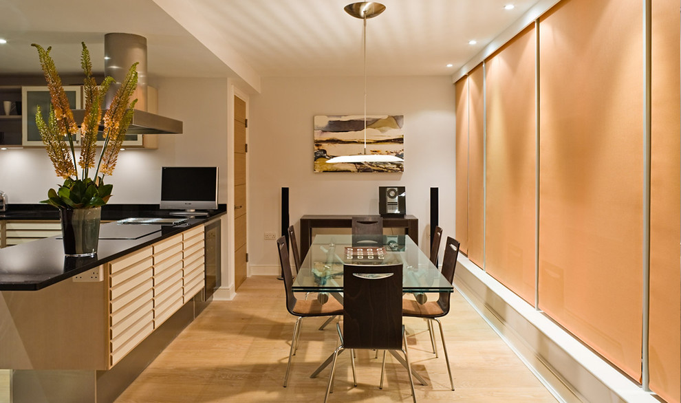 This is an example of a medium sized contemporary l-shaped kitchen/diner in London with a submerged sink, recessed-panel cabinets, light wood cabinets, granite worktops, black splashback, ceramic splashback, stainless steel appliances, ceramic flooring and a breakfast bar.
