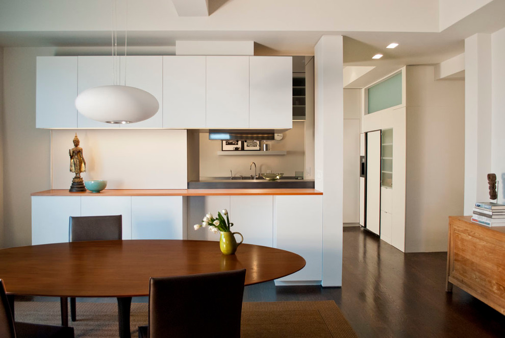 На фото: кухня в современном стиле с плоскими фасадами, обеденным столом и оранжевой столешницей с
