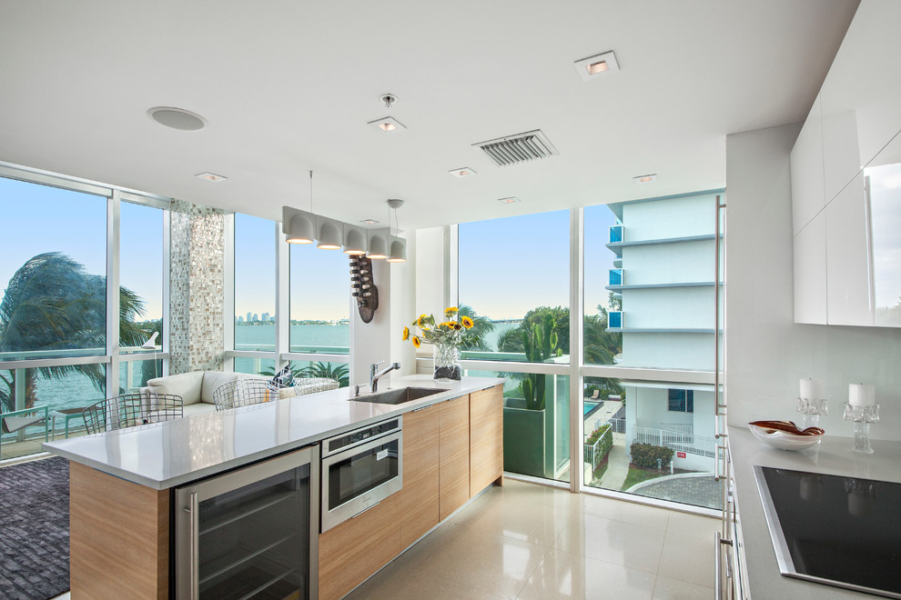 Стильный дизайн: параллельная кухня-гостиная в стиле модернизм с белыми фасадами, зеркальным фартуком и островом - последний тренд