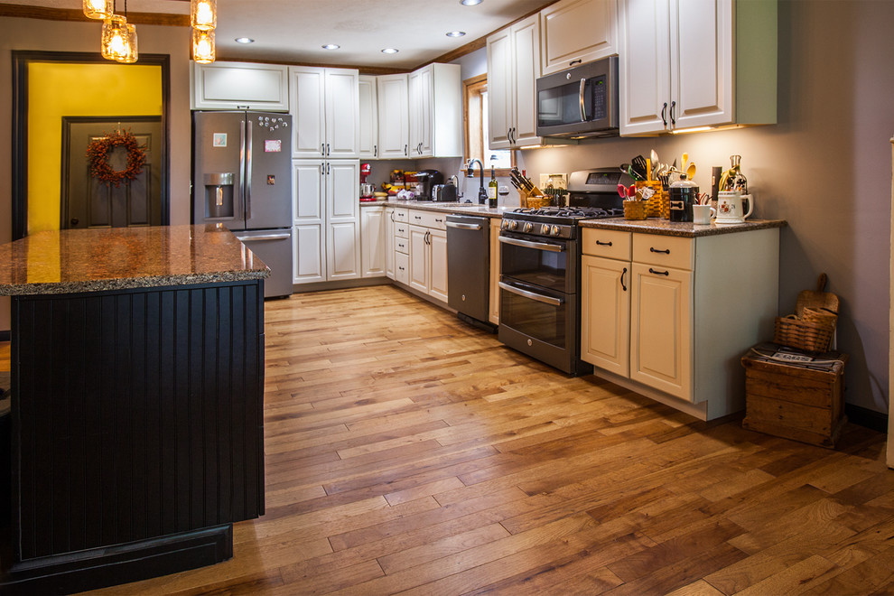 Immagine di una cucina classica di medie dimensioni con ante con bugna sagomata, ante bianche, elettrodomestici in acciaio inossidabile e pavimento in legno massello medio