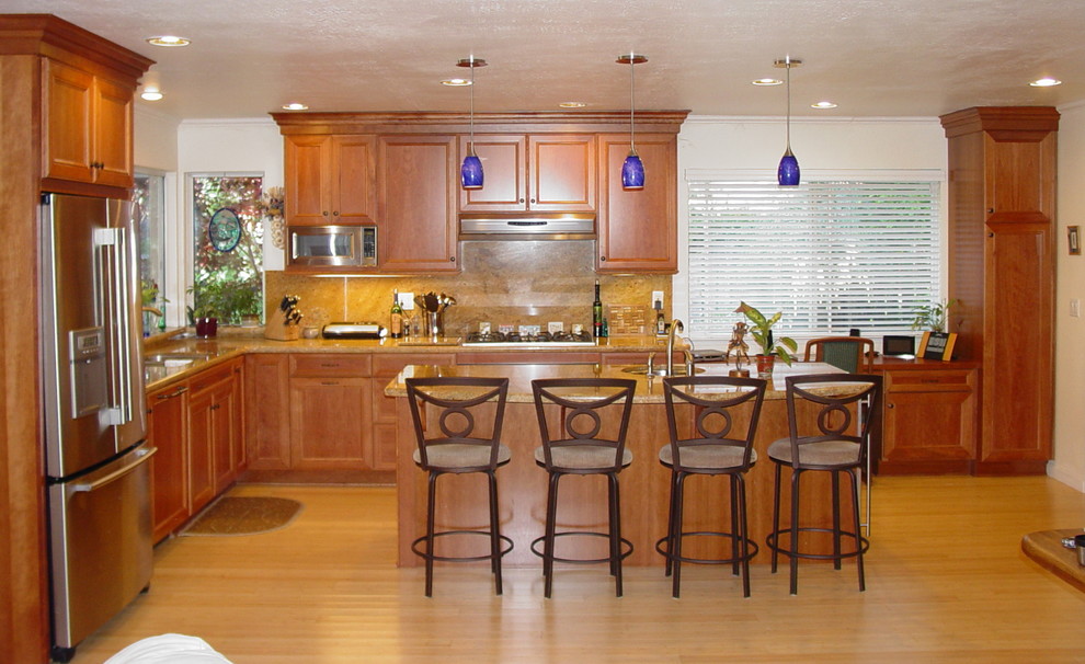 Mid-sized transitional l-shaped bamboo floor eat-in kitchen photo in San Francisco with an undermount sink, recessed-panel cabinets, medium tone wood cabinets, granite countertops, yellow backsplash, stone slab backsplash, stainless steel appliances and an island