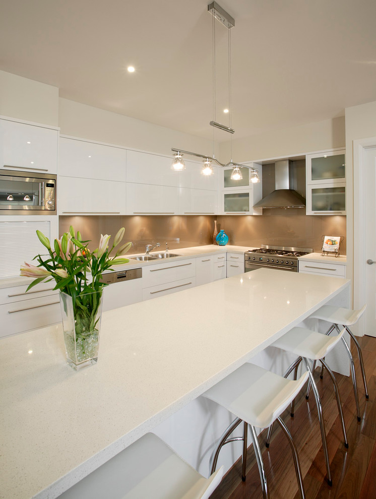 Inspiration for a medium sized contemporary galley kitchen/diner in Sydney with a submerged sink, flat-panel cabinets, white cabinets, quartz worktops, brown splashback, glass sheet splashback, stainless steel appliances, medium hardwood flooring and an island.
