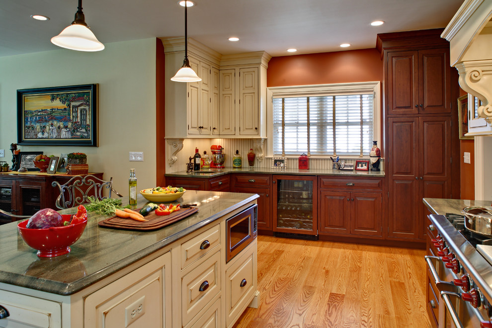 Inspiration for a large timeless l-shaped medium tone wood floor and brown floor eat-in kitchen remodel in Newark with an undermount sink, raised-panel cabinets, medium tone wood cabinets, granite countertops, green backsplash, glass tile backsplash, stainless steel appliances and an island