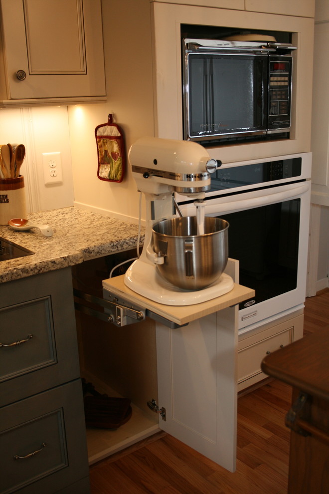Inredning av ett lantligt litet kök, med vita skåp, granitbänkskiva, flerfärgad stänkskydd, rostfria vitvaror, en dubbel diskho, mellanmörkt trägolv och släta luckor