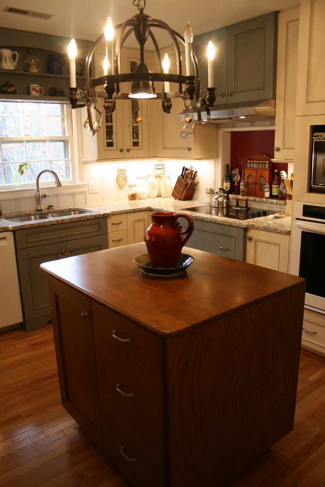 Bild på ett mellanstort lantligt kök, med en dubbel diskho, släta luckor, vita skåp, granitbänkskiva, flerfärgad stänkskydd, rostfria vitvaror och ljust trägolv