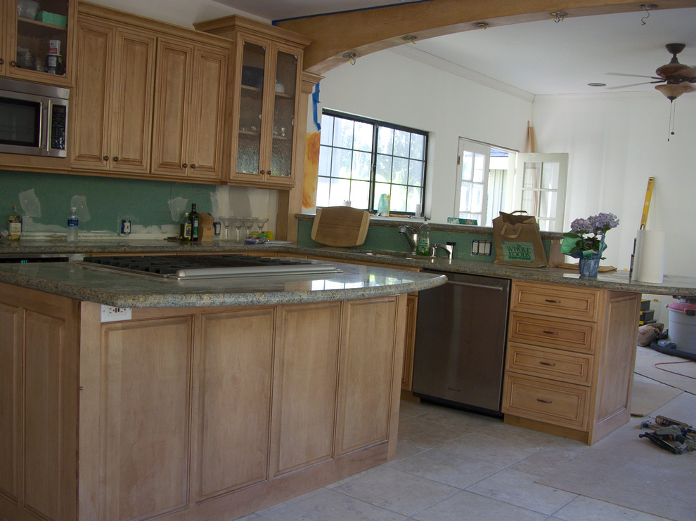 Bild på ett mellanstort lantligt kök, med en undermonterad diskho, luckor med upphöjd panel, skåp i mellenmörkt trä, granitbänkskiva, rostfria vitvaror, travertin golv och flera köksöar