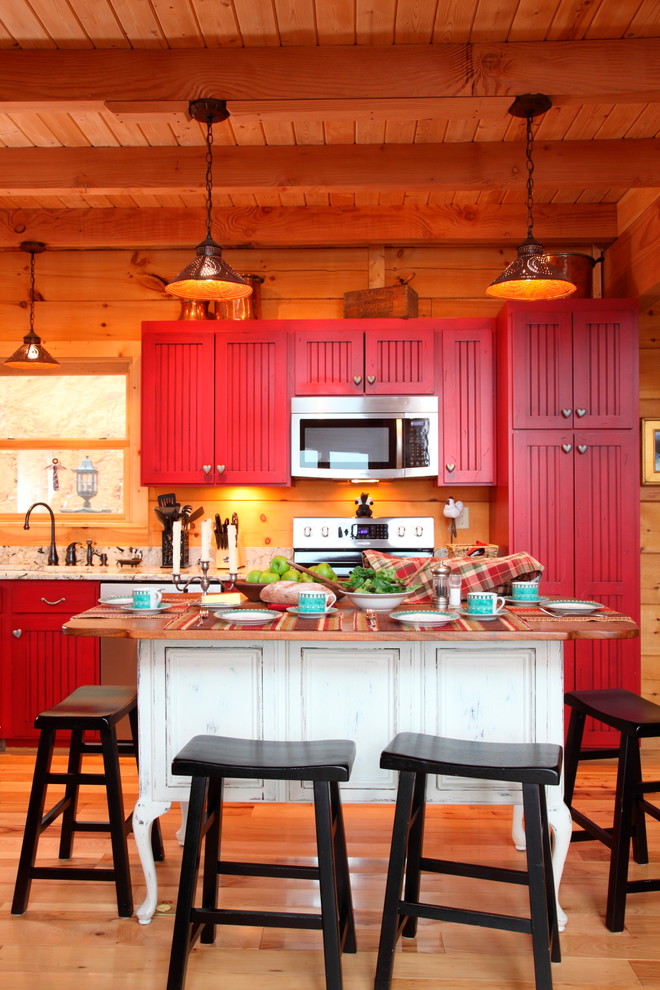 Bild på ett rustikt linjärt kök med öppen planlösning, med rostfria vitvaror, röda skåp och mellanmörkt trägolv