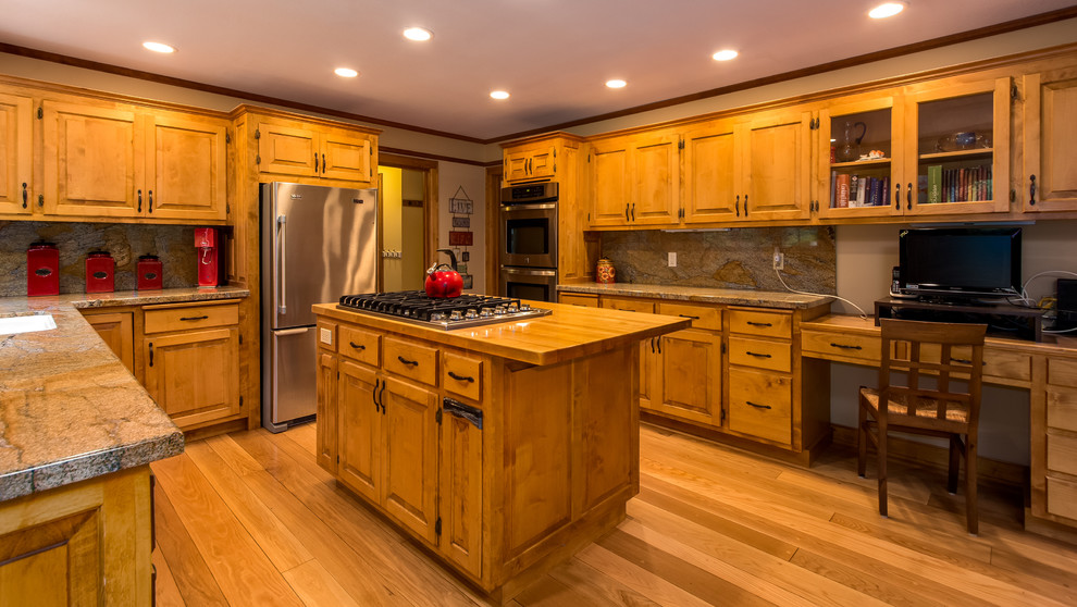 Bild på ett stort lantligt kök, med en undermonterad diskho, luckor med upphöjd panel, skåp i mellenmörkt trä, träbänkskiva, stänkskydd i sten, rostfria vitvaror, mellanmörkt trägolv och en köksö