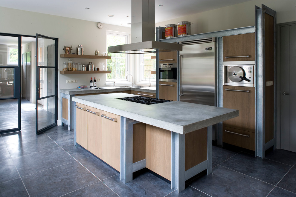 Imagen de cocina contemporánea con armarios con paneles lisos, encimera de cemento, electrodomésticos de acero inoxidable y puertas de armario de madera clara