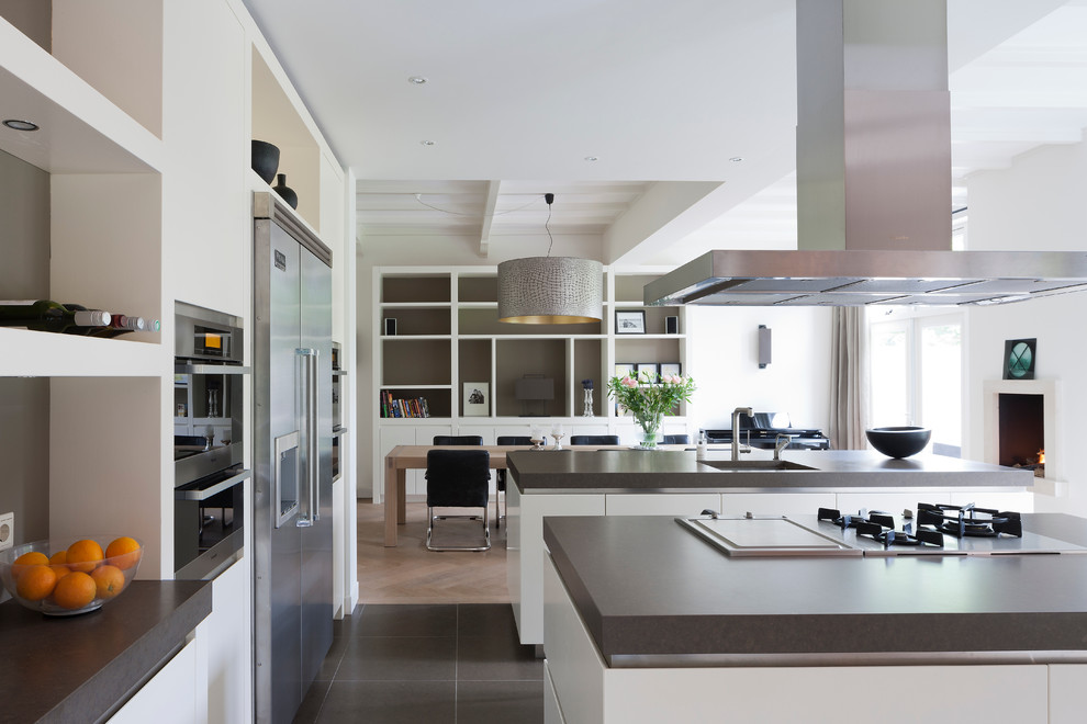Photo of a contemporary kitchen/diner in New York with a submerged sink, flat-panel cabinets, white cabinets and stainless steel appliances.