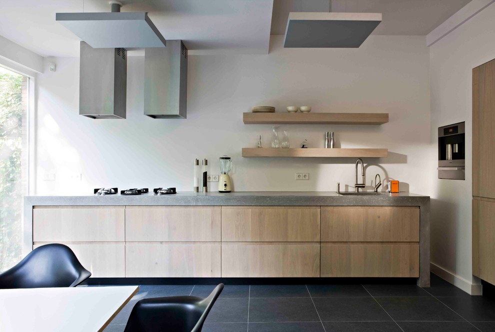 На фото: угловая кухня в современном стиле с обеденным столом, монолитной мойкой, плоскими фасадами, светлыми деревянными фасадами, техникой из нержавеющей стали и окном