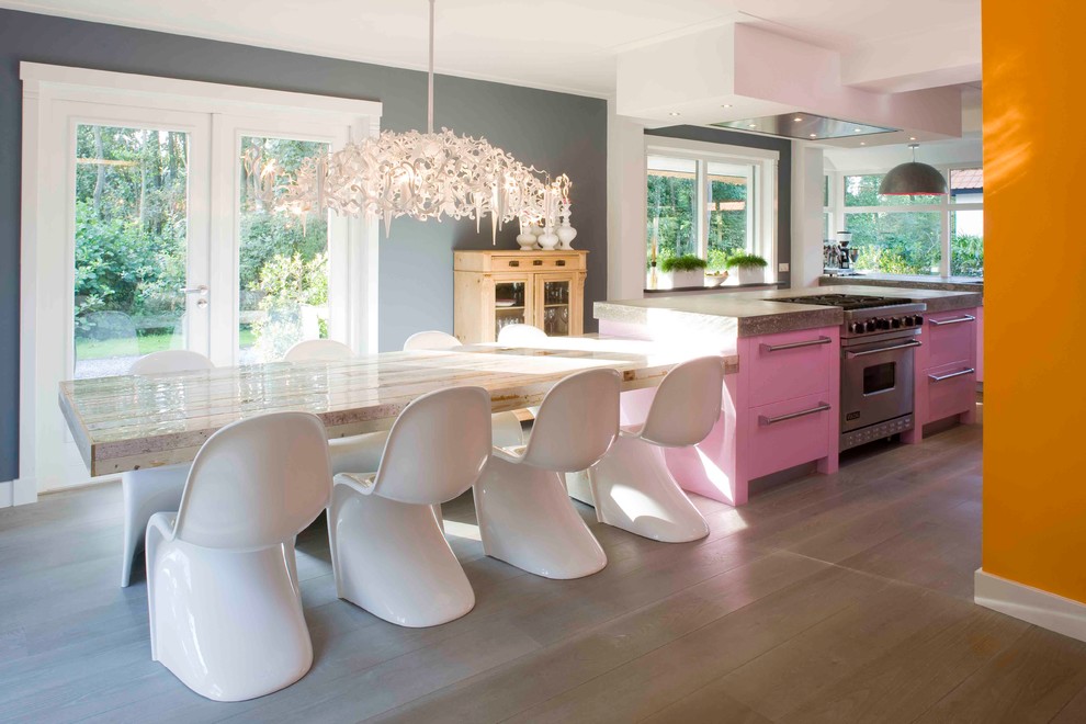 Exemple d'une grande cuisine américaine grise et rose tendance en L avec un placard à porte plane, un électroménager en acier inoxydable, un évier encastré, un plan de travail en béton, un sol en bois brun et îlot.