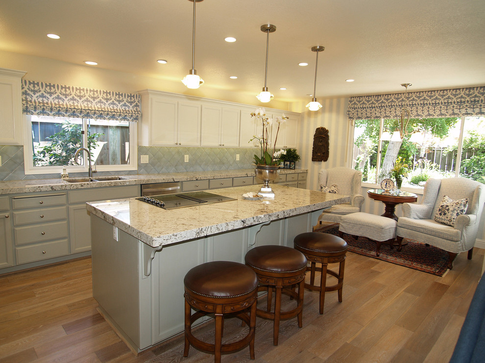 Mid-sized elegant single-wall light wood floor open concept kitchen photo in Sacramento with an undermount sink, recessed-panel cabinets, white cabinets, granite countertops, blue backsplash, terra-cotta backsplash, stainless steel appliances and an island