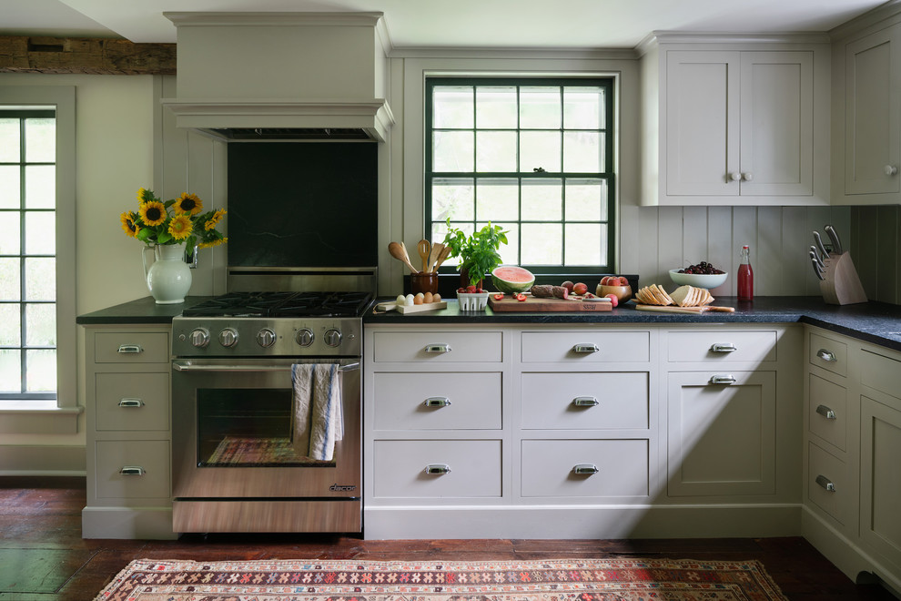 Esempio di una cucina abitabile classica con ante in stile shaker, ante beige, paraspruzzi beige, elettrodomestici in acciaio inossidabile, pavimento in legno massello medio, pavimento marrone e top nero