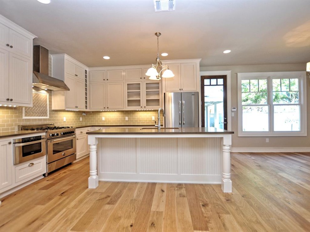 Inspiration for a craftsman l-shaped light wood floor open concept kitchen remodel in Austin with an undermount sink, beaded inset cabinets, white cabinets, quartz countertops, beige backsplash, subway tile backsplash, stainless steel appliances and an island