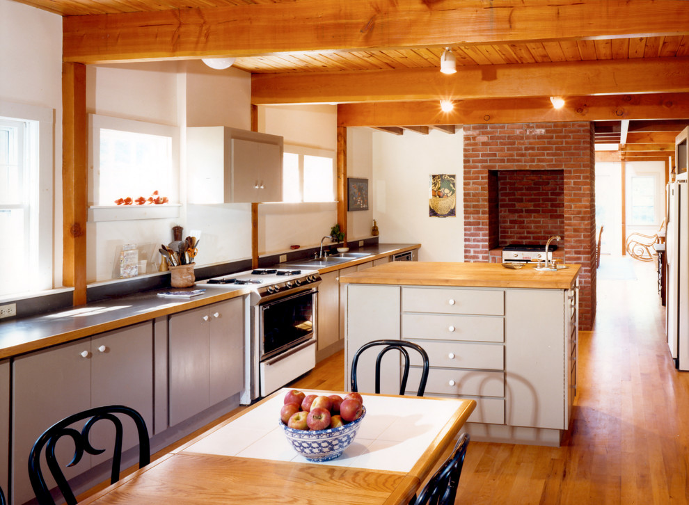 Foto på ett lantligt kök och matrum, med släta luckor, grå skåp, träbänkskiva, vita vitvaror, en dubbel diskho, mellanmörkt trägolv och en köksö