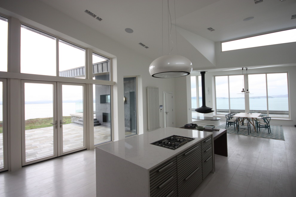 Imagen de cocina contemporánea con encimera de mármol, electrodomésticos de acero inoxidable, suelo de madera clara, una isla y suelo blanco