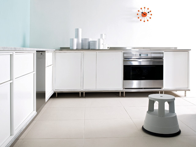 Diseño de cocinas en L moderna con armarios con paneles lisos, puertas de armario blancas, encimera de piedra caliza y electrodomésticos de acero inoxidable