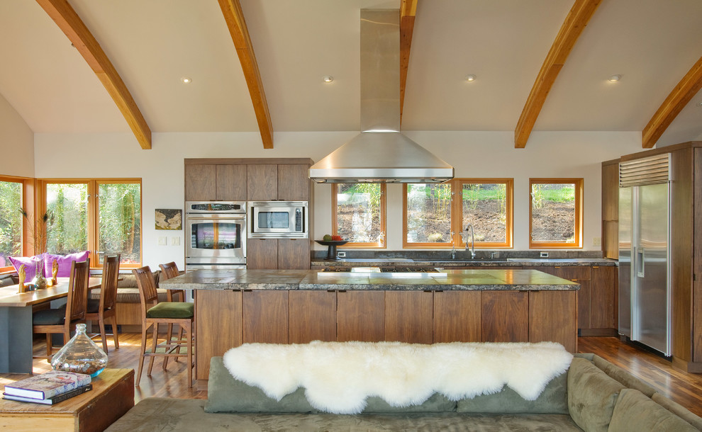 Imagen de cocina contemporánea abierta con armarios con paneles lisos, puertas de armario de madera en tonos medios y electrodomésticos de acero inoxidable