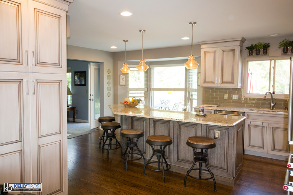 Eat-in kitchen - large transitional l-shaped medium tone wood floor eat-in kitchen idea in Cincinnati with an undermount sink, raised-panel cabinets, white cabinets, granite countertops, gray backsplash, subway tile backsplash, stainless steel appliances and an island