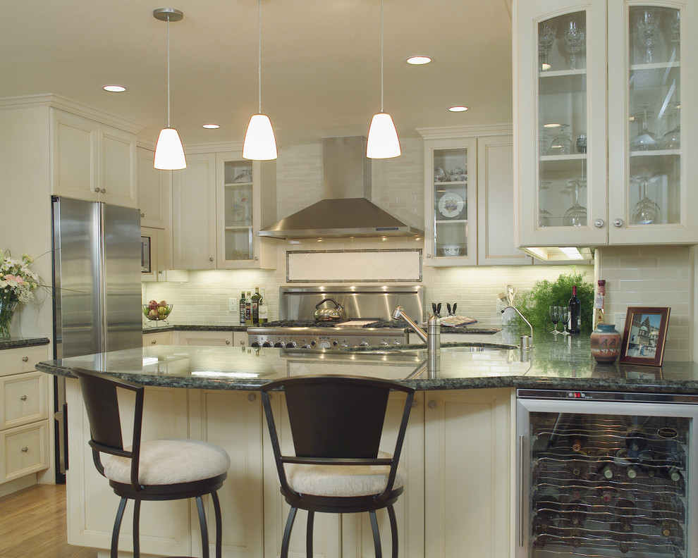 Elegant u-shaped kitchen photo in San Francisco with glass-front cabinets, stainless steel appliances, granite countertops, an undermount sink, beige cabinets, beige backsplash and subway tile backsplash