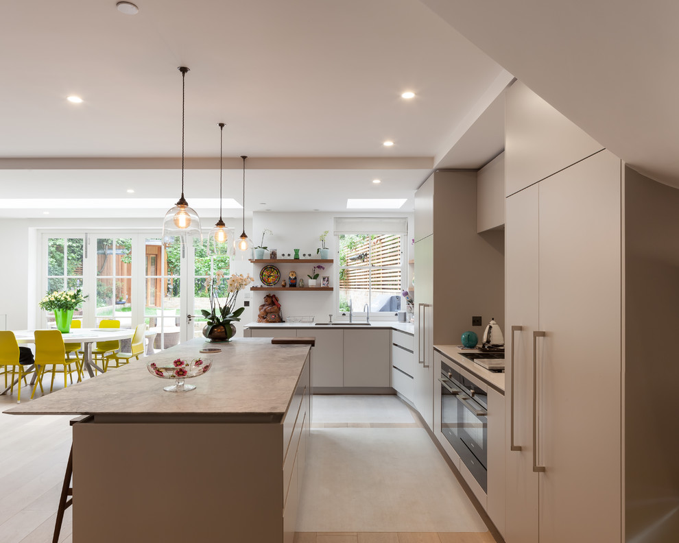 This is an example of a medium sized contemporary l-shaped kitchen/diner in London with a built-in sink, flat-panel cabinets, white cabinets, marble worktops, brown splashback, wood splashback, coloured appliances, light hardwood flooring, an island and brown floors.