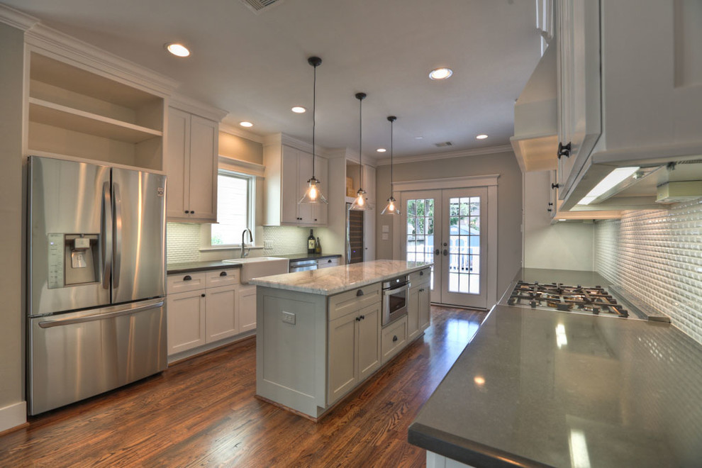 Example of a classic eat-in kitchen design in Houston with a farmhouse sink, white cabinets, marble countertops, white backsplash and stainless steel appliances