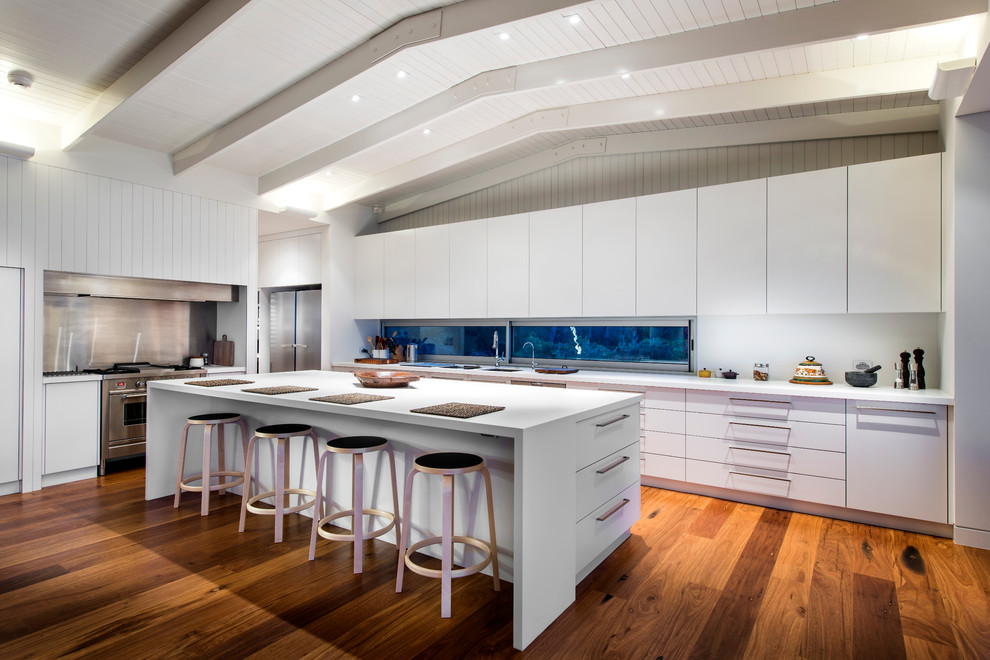 Esempio di una cucina design con lavello sottopiano, ante lisce, ante bianche, elettrodomestici in acciaio inossidabile e pavimento in legno massello medio