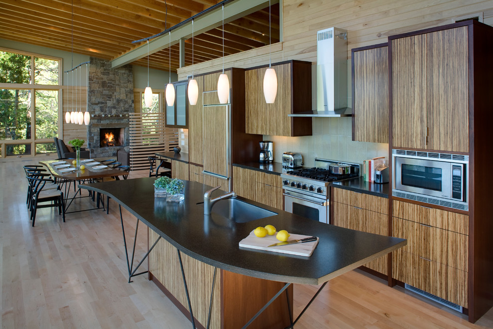 Kitchen - small modern galley light wood floor kitchen idea in Seattle with paneled appliances, an undermount sink, medium tone wood cabinets, solid surface countertops, porcelain backsplash and an island