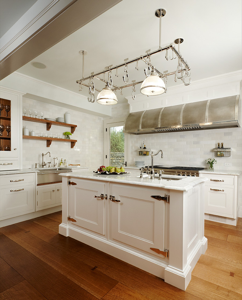 Foto på ett vintage l-kök, med rostfria vitvaror, en rustik diskho, skåp i shakerstil, vita skåp, marmorbänkskiva, vitt stänkskydd, stänkskydd i porslinskakel, mellanmörkt trägolv och en köksö