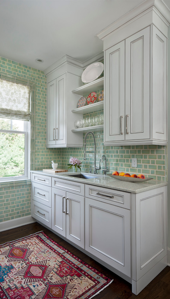 Inredning av ett klassiskt kök, med luckor med infälld panel, grå skåp, grönt stänkskydd, mörkt trägolv, en enkel diskho, granitbänkskiva, stänkskydd i porslinskakel och rostfria vitvaror