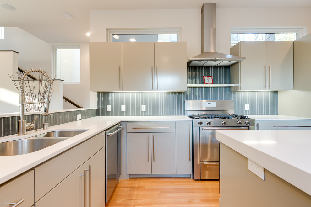 ダラスにあるコンテンポラリースタイルのおしゃれなキッチン (シルバーの調理設備、青いキッチンパネル、ダブルシンク、フラットパネル扉のキャビネット、白いキャビネット) の写真