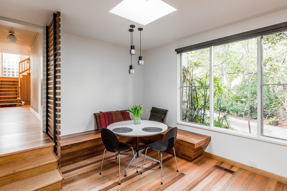 Example of a trendy medium tone wood floor eat-in kitchen design in Melbourne with an undermount sink, flat-panel cabinets, black cabinets, quartz countertops, orange backsplash, cement tile backsplash, stainless steel appliances and no island