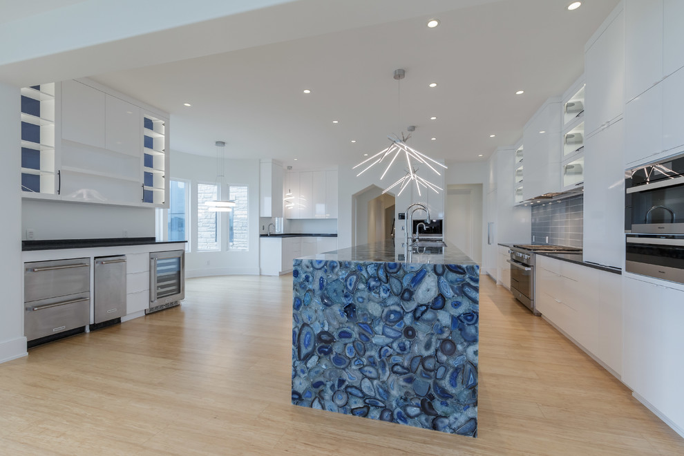 Example of a large trendy galley light wood floor open concept kitchen design in Other with an undermount sink, flat-panel cabinets, white cabinets, blue backsplash, ceramic backsplash, paneled appliances, an island and blue countertops