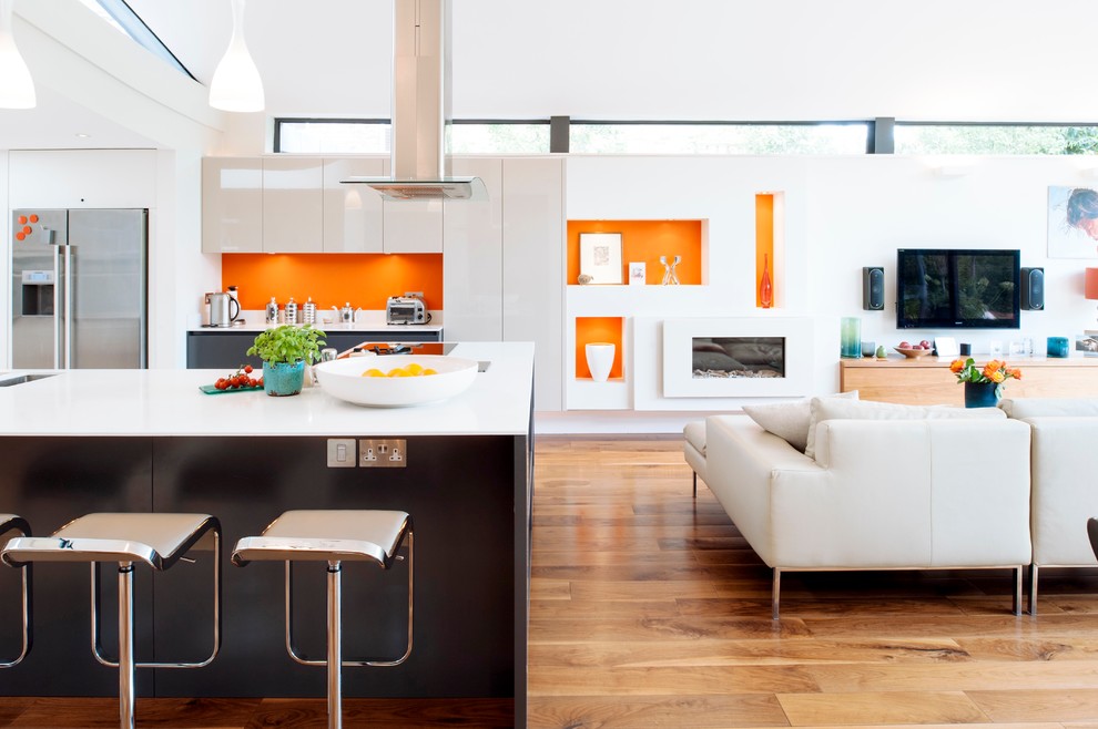Cette image montre une cuisine design avec un placard à porte plane, des portes de placard grises, un sol en bois brun et îlot.
