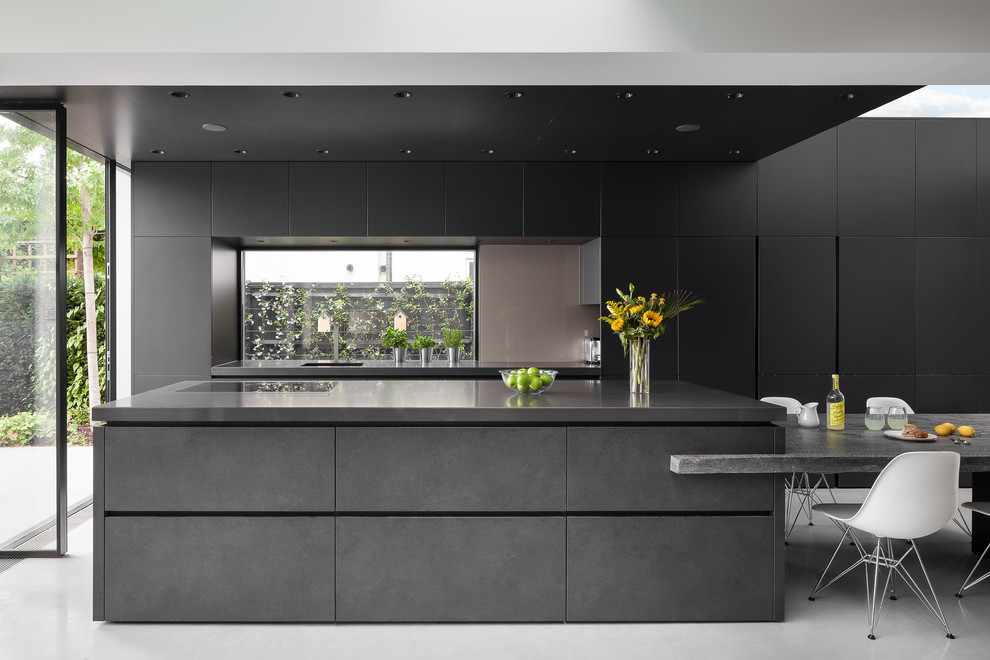 Moderne Küche mit flächenbündigen Schrankfronten, Mineralwerkstoff-Arbeitsplatte, Betonboden, grauem Boden, Waschbecken, schwarzen Schränken, Rückwand-Fenster und zwei Kücheninseln in London